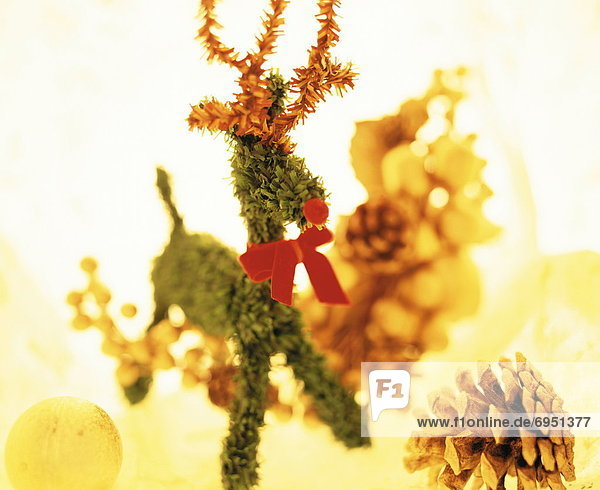 Reindeer Christmas ornament surrounded by baubles and pine cones