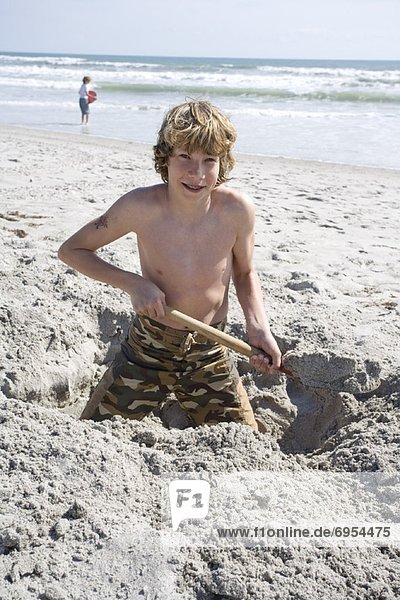 Vereinigte Staaten von Amerika USA Strand Junge - Person Sand graben gräbt grabend