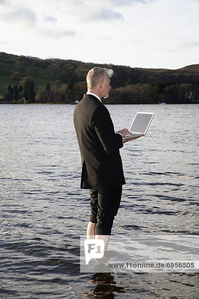 Businessman with Laptop Computer Standing in Lake Windermere  Cumbria  England