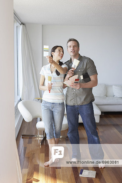 Couple in Apartment with Paint Brushes and Color Swatches