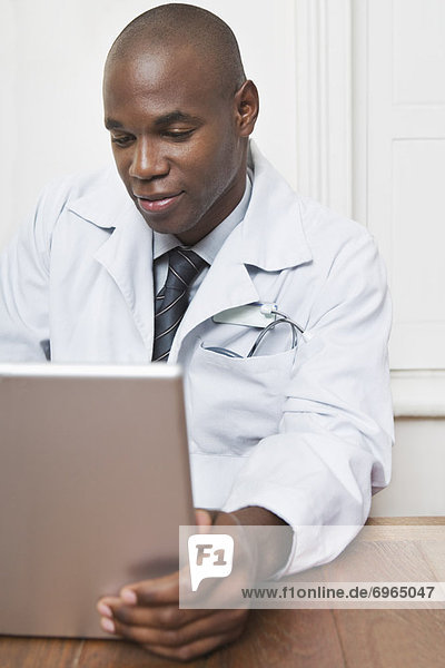 Physician Sitting Behind Desk Working on Laptop