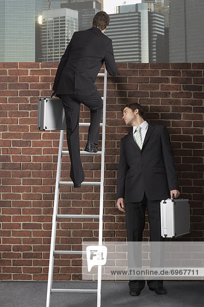 Businessman Climbing Ladder Over Brick Wall While Other Businessman Looks On