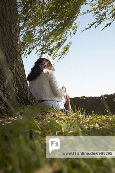Woman Reading a Book Underneath a Willow Tree