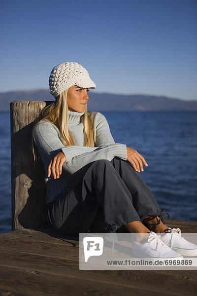 Woman Sitting On Dock by Lake