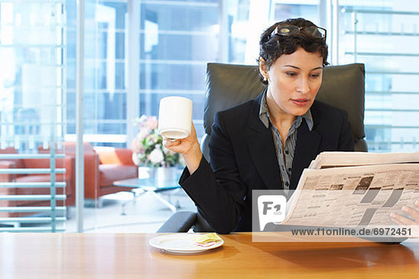 Businesswoman Reading Newspaper at Desk