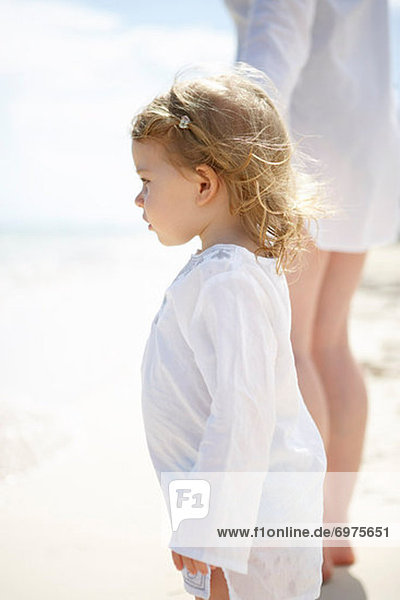 Little Girl Holding Mothers Hand and Walking on Beach
