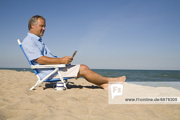 Man Sitting on the Beach Using His Cell Phone  Lake Michigan  USA