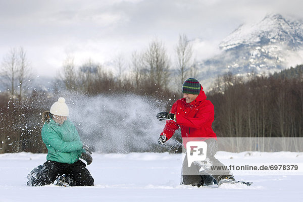 Couple Wearing Snowshoes having a Snowball Fight  Whistler  Bristish Columbia  Canada