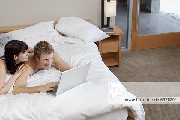 Couple in Bed Using Laptop Computer