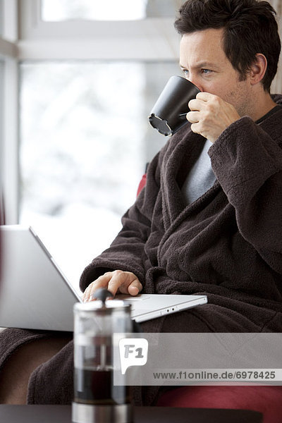benutzen Mann Computer Notebook Tasse Bademantel trinken Kaffee