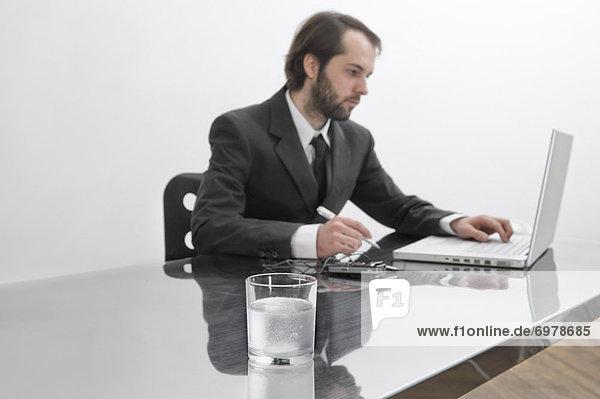 Tablets Dissolving in Glass of Water on Businessmans Desk