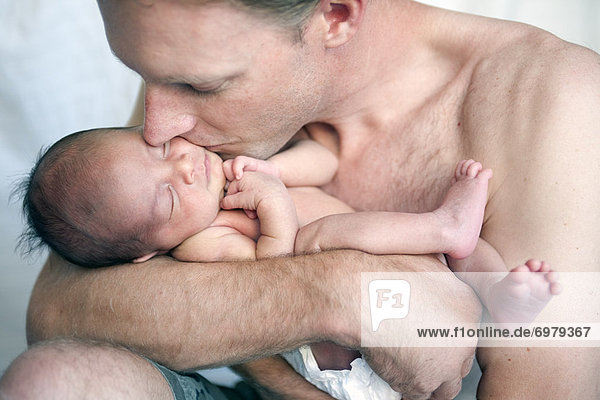 Father Holding and Kissing Sleeping Newborn Baby