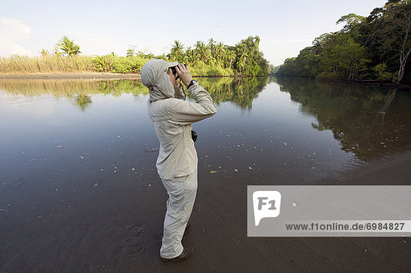 Wanderin mit Fernglas an der Mündung des Rio Sirena  Sirena  Nationalpark Corcovado  Provinz Puntarenas  Costa Rica  Zentralamerika