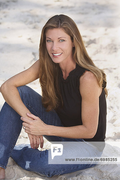 Portrait of Woman Sitting on Beach  Wearing Blue Jeans