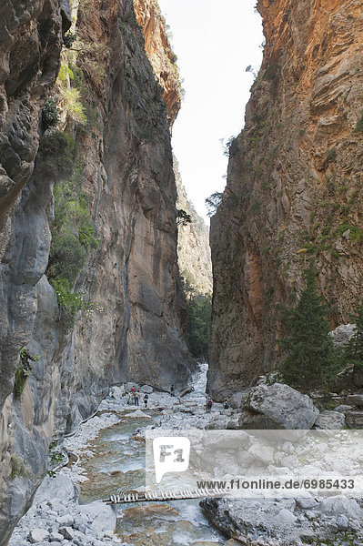 Steep cliffs rise up above the rocky bed of a stream  several hikers  boardwalks  3rd Gate  Iron Gate  view towards the south  Samaria Gorge National Park  near Agia Roumeli  Crete  Greece  Europe
