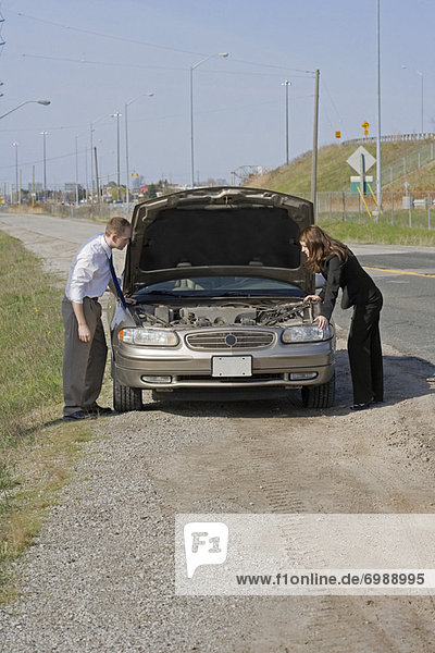 Man and Woman With Car Trouble Looking Under the Hood