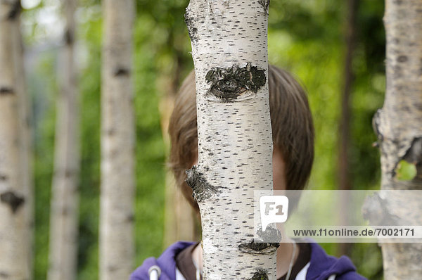 Boy Hidden Behind Tree trunk