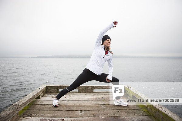 Woman Stretching on Dock before Jogging  Puget Sound  Seattle  Washington  USA