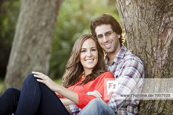 Portrait of Young Couple Sitting in Park