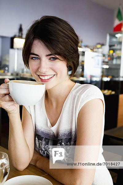 Lächelnde Frau trinkt Kaffee im Café