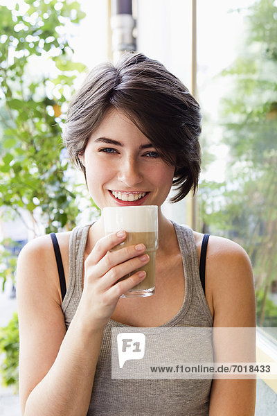 Lächelnde Frau trinkt Kaffee im Freien