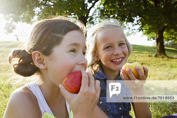 Lachende Mädchen essen Äpfel im Freien.