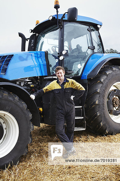 Farmer standing by tractor in field