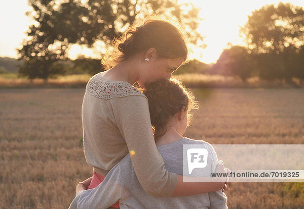Mutter und Tochter umarmen sich im Feld