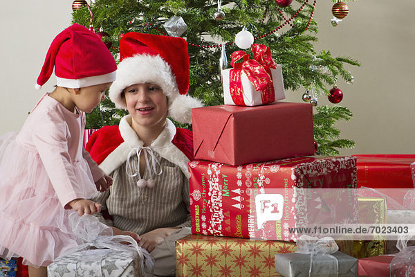 Junge Geschwister bereiten sich darauf vor  Weihnachtsgeschenke zu öffnen.