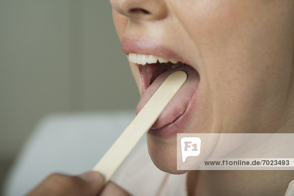 Frau  die den Mund mit Zungenspatel untersucht hat  abgeschnitten