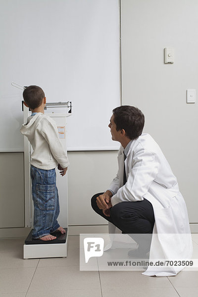 Little boy standing on weight scale in doctor's office