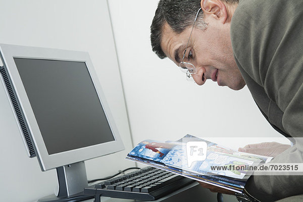 Mature man reading comic book at desk in office