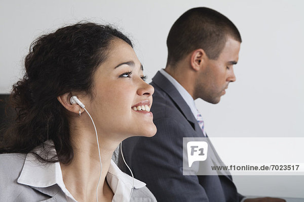 Woman listening to earphones and daydreaming in office