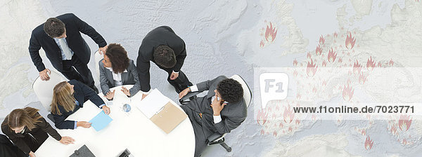 Executives in meeting  large map depicting European economic crisis in background