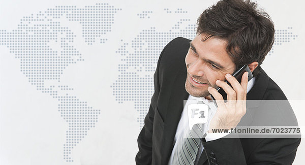 Businessman talking on cell phone  world map in background