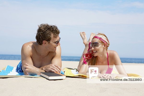 Young couple relaxing on beach mats