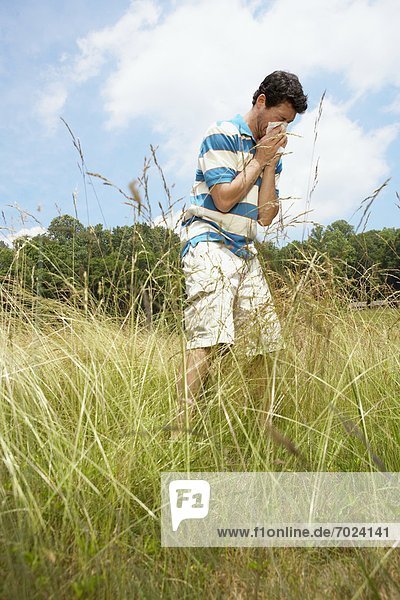 Man blowing nose in field (low angle view)
