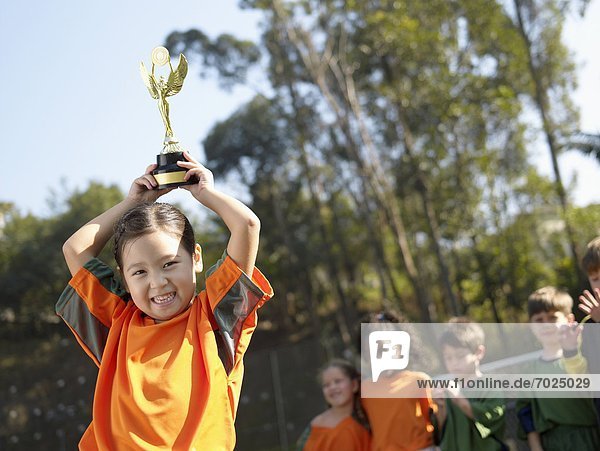 Girl holding trophy  soccer team in background (portrait)