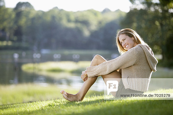 Frau sitzt auf Rasen