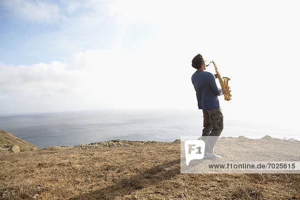 Man playing saxophone on cliff