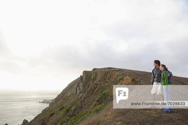 Young couple looking at sea on cliff
