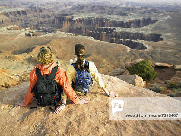 Young couple with backpacks sitting on rock