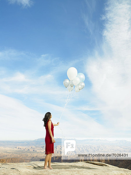 Mid adult woman holding balloons  rock strata in background