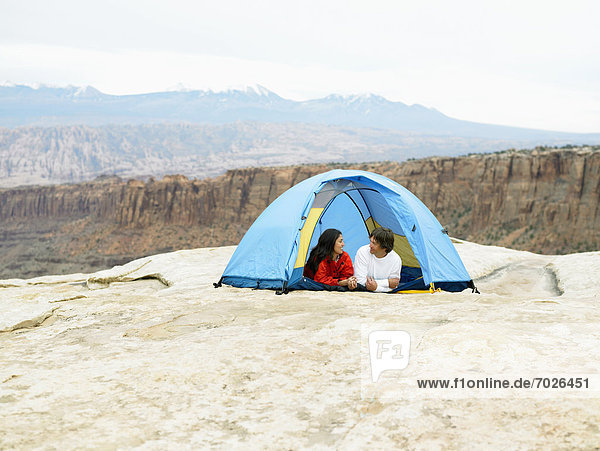 Couple in tent  rock strata in background  Moab  Utah  USA