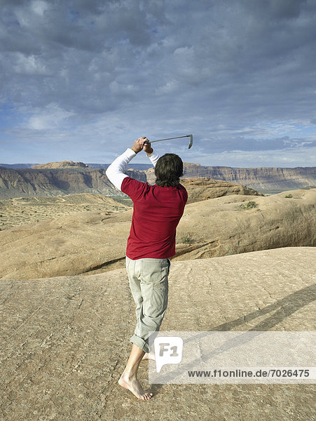 Man playing golf in desert  rear view