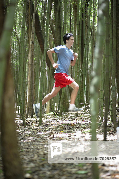 Young man running in forest