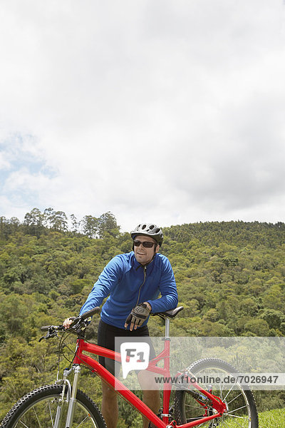 Male cyclist leaning on mountain bike