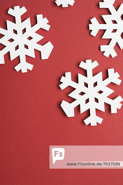 Paper snowflakes on red background (close-up)