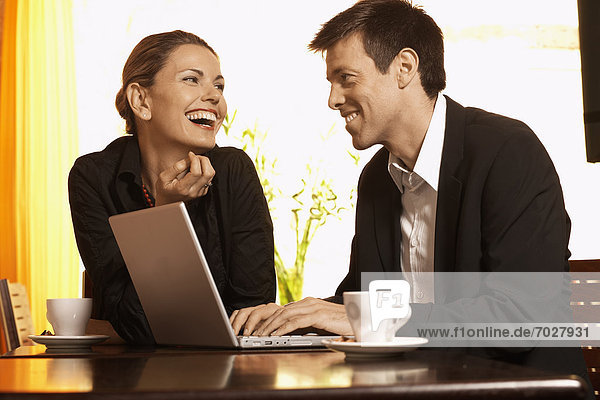 Man and woman using laptop in cafe (low angle view)