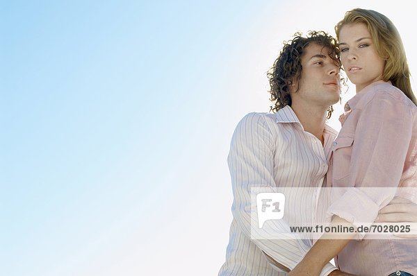 Young couple against clear sky (portrait  low angle view)